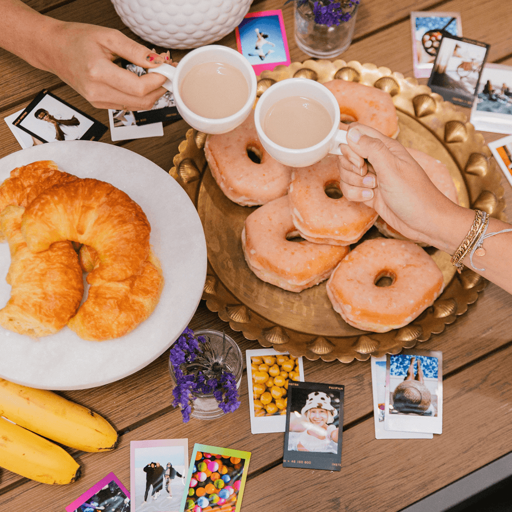 instax mini film op tagel met doughnust op een schaal twee bananen en croissants op een bord