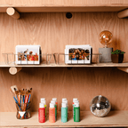 Sfeerafbeelding instax™ WIDE film, waarin de foto's in een mandje op een plank staan. Verder zijn er knutselspulletjes zichtbaar, de foto geeft een knusse sfeer.